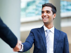 Man wearing a suit smiling and handshaking